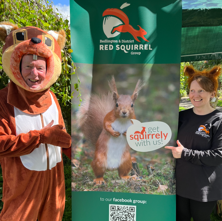 Man in squirrel costume and lady in squirrel hat standing either side of a printed roller banner